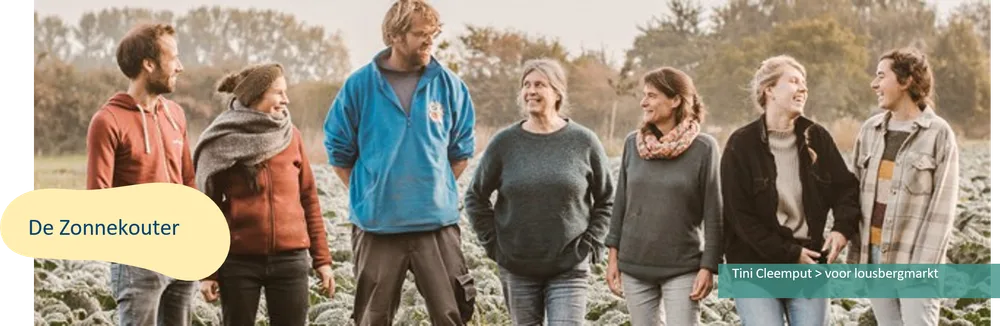 Zes mensen staan lachend naast mekaar op een veld met gewassen. Op de foto staat "De Zonnekouter" en "Tini Cleemput > voor lousbergmarkt".