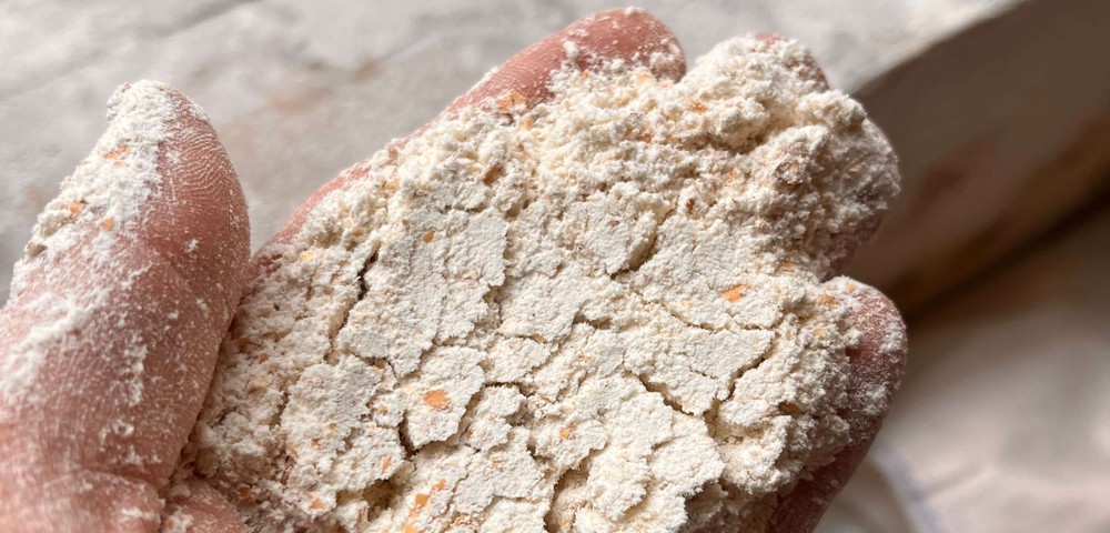 Hand holding cracked, powdery flour near a window